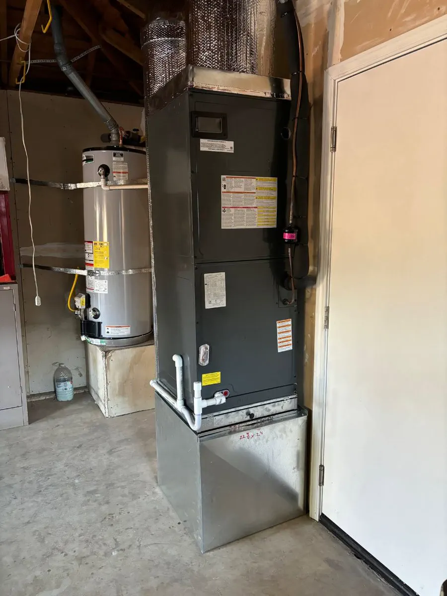 A new furnace and air handler installed on a metal stand in a garage